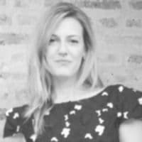 Bu görüntüde siyah beyaz bir elbise giyen bir kadın görülüyor. Kadın iyi aydınlatılmış bir alanda ayakta durmakta ve vücudu kameraya doğru bakmaktadır. Elleri belinin önünde hafifçe kavuşturulmuş. Yüzünde nazik bir gülümsemeyle yana bakıyor gibi görünüyor. Siyah elbisesinin üst yarısı beyaz desenli, alt yarısı ise düz siyahtır. Elbisenin V yakası ve bileklerine kadar uzanan uzun kolları vardır. Saçları düzgün bir topuzla geriye doğru toplanmış ve bir çift küçük siyah küpe takıyor. Kıyafetinin içinde zarif ve kendinden emin görünüyor.