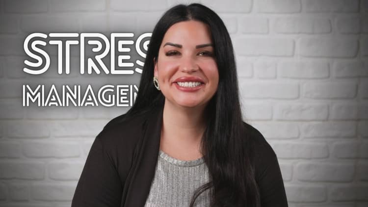 A woman explaining a stress management course. In the foreground she is giving academic information about stress management. woman standing in front of a brick wall with stress management sign, dark beige and silver style, progressive artist movement, smilecore, video montages, george stefanescu, chicano inspired, website --ar 16:9