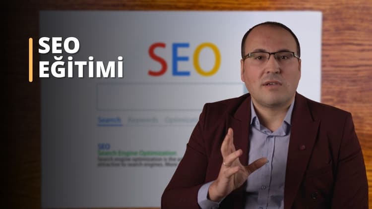 Bu görüntü SEO (Arama Motoru Optimizasyonu) hakkında bir çevrimiçi kursu yansıtıyor. Bir ekranın önünde konuşan takım elbiseli bir adam görülüyor. Adam gözlük ve kahverengi bir gömlek giyiyor ve sağ eliyle bir şeyi işaret ediyor. Arka planda, beyaz metinli bir tabelanın yakın çekimi ve beyaz zemin üzerinde sarı bir sayı var. SEO eğitimi ve kursları, işletmelerin web sitelerini ve içeriklerini arama motorları için nasıl optimize edeceklerini daha iyi anlamalarına yardımcı olabilir. Doğru SEO teknikleri sayesinde işletmeler arama motoru sonuç sayfalarında daha üst sıralarda yer alarak web sitelerine daha fazla trafik çekebilir ve daha fazla müşteri kazanabilirler. SEO kurslarının yardımıyla işletmeler, anahtar kelimeleri stratejik olarak nasıl kullanacaklarını, arama motoru algoritmalarına hitap eden içerikleri nasıl oluşturacaklarını ve çevrimiçi pazarlamanın nüanslarını nasıl anlayacaklarını öğrenebilirler.