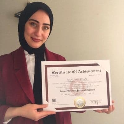 Elinde İstanbul işletme Enstütüsü sertifikası olan bir kadın görünüyor. arka plan beyaz duvar. Onaylı sertifika aldığı için mutlu olduğu anlaşılıyor.