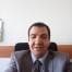 Bu, şık giyimli bir adamın görüntüsüdür. Kendisine tam oturacak şekilde dikilmiş koyu gri bir takım elbise giyiyor. Gıcır gıcır beyaz gömleği takım elbisenin içinde göze çarpıyor ve siyah kravatı düzgünce düğümlenmiş. Saçları kısa ve yana doğru taranmış ve bir çift siyah ayakkabı giyiyor. Elleri cebinde dururken kendinden emin ve profesyonel görünüyor. Yüzünde ciddi bir ifade var ama gözleri parıldıyor. Dünyayı ele geçirmeye hazır bir adam gibi görünüyor.
