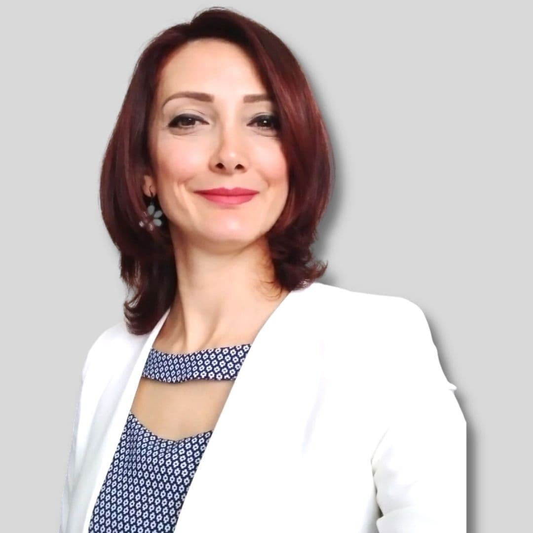 The photo shows a woman with a bright, warm smile, looking directly at the camera. Her eyes are bright and her lips are slightly parted, indicating her cheerful nature. She is wearing a white jacket, which is a classic garment for teachers. The photo is a close-up of her face and chest, with her eyes and nose clearly visible. Her facial features are composed and her hair is neatly styled, giving the impression of a competent and professional instructor. The photo also showcases her beauty and personality, suggesting she has the qualities of a great teacher. The photo gives a sense of confidence, respect, and friendliness, making it the perfect image to represent a course instructor.
