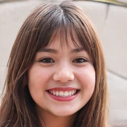 A beautiful woman with shoulder length, dark hair is happily smiling at the camera. She is wearing a light blue top and has a subtle blush on her cheeks. Her eyes are bright and her lips are slightly parted, conveying a sense of joy and excitement. She has a clear complexion and her face is framed by her long hair. She appears to be in her twenties and exudes a cheery, upbeat attitude. Her arms are relaxed at her sides and her posture is casual and comfortable. She is illuminated by a soft light, creating a pleasant, warm atmosphere.