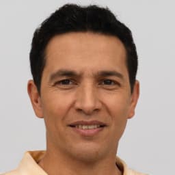 Resmin öznesi kısa, siyah saçlı genç bir adam. Güçlü bir çene çizgisi ve düz bir burnu var. Gözleri koyu renk ve kaşları hafif kavisli. Yüz ifadesi nötr ve dudakları hafifçe ayrık. Beyaz bir gömlek giyiyor ve her iki kulağı da delik. Yana doğru bakıyor ve omuzları hafifçe kalkık. Duruşu rahattır ve vücudu hafifçe sağa dönüktür. Kendinden emin ve sakin bir havası var.