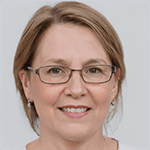 A woman with short, dark hair and glasses is smiling brightly, her cheeks rosy and her eyes bright with joy. She has a white shirt tucked into a pair of black trousers and a pair of black shoes. Her glasses are thin, black frames that contrast against her pale skin. Her lips are curved upwards in a genuine smile, revealing a set of white teeth. She is standing in front of a wooden wall, a warm yellow light illuminating the scene. Her expression radiates joy and positivity, conveying a feeling of contentment and satisfaction.